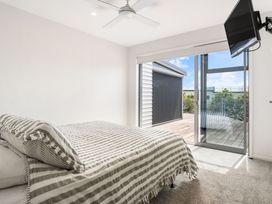 A bedroom with a bed and a sliding door at Happy Place - Waihi Beach Holiday Home Waihi Beach