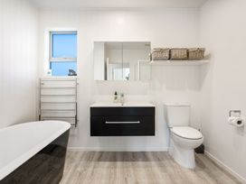 A bathroom with a bathtub and vanity at Happy Place - Waihi Beach Holiday Home, Waihi Beach