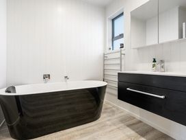 A bathroom with a bathtub and vanity at Happy Place - Waihi Beach Holiday Home, Waihi Beach