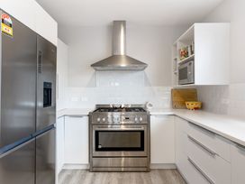 A kitchen with a refrigerator, oven, and microwave at Happy Place - Waihi Beach Holiday Home, Waihi Beach