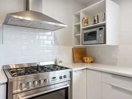 A kitchen with a stove, oven, microwave, cutting board, and bowl at Happy Place - Waihi Beach Holiday Home