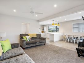 A living room with a sofa and kitchen view at Happy Place - Waihi Beach Holiday Home, Waihi Beach