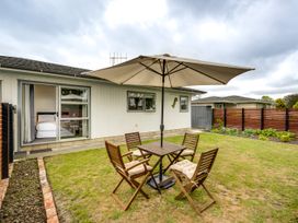 A garden with a table and chairs under an umbrella at Cozy on Clive - Hastings