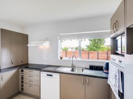 A kitchen with cabinets, sink, stove, and appliances at Cozy on Clive - Hastings Holiday Home