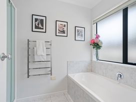 A bathroom with a bathtub and towel rack at Papamoa Beach in Papamoa