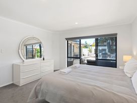 A bedroom with a bed and sliding doors leading to an outdoor area at Papamoa Beach in Papamoa