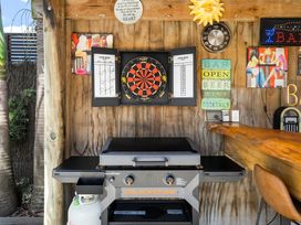 An outdoor kitchen with a grill and dartboard at Papamoa Beach in Papamoa