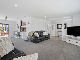 A living room with a black sofa and television at Papamoa Beach in Papamoa