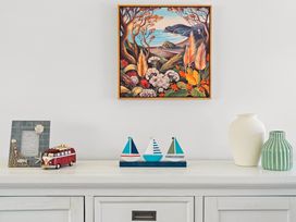 A table with a picture frame, artwork, toy bus, sailboats, and vases at Papamoa Beach in Papamoa