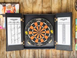 A dartboard with menu boards on the side in a game area at Papamoa Beach, Papamoa