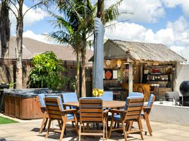 An outdoor dining area with a hot tub and barbecue grill at Papamoa Beach in Papamoa