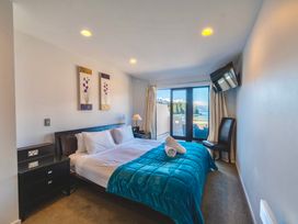 A bedroom with a bed and balcony door at Lakefront Penthouse - Central Queenstown Holiday Home, Queenstown