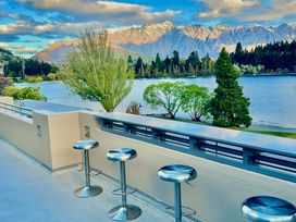 An outdoor area with bar stools overlooking a lake at Lakefront Penthouse - Central Queenstown Holiday Home in Queenstown
