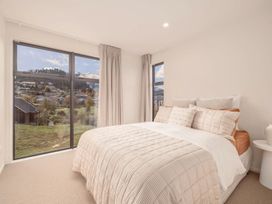 A bedroom with a bed and windows at Hanmer Alpine - Hanmer Holiday Home Hanmer Springs