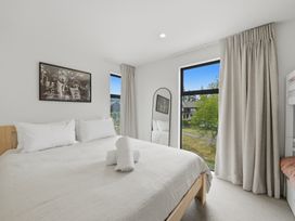A bedroom with a bed and windows at Hanmer Alpine Chalet - Hanmer Holiday Home