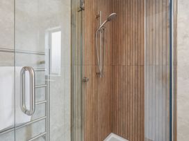 A shower with glass door and wooden panels at Hanmer Alpine Chalet - Hanmer Holiday Home