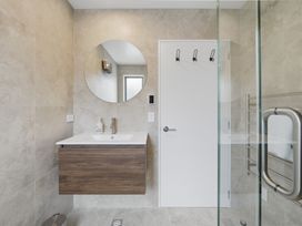 A bathroom with a sink, mirror, and shower at Hanmer Alpine Chalet - Hanmer Holiday Home