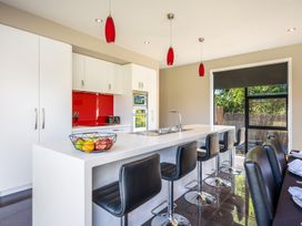 A kitchen with a countertop, bar stools, and kitchen appliances at Lake Hawea Holiday Home in Wanaka