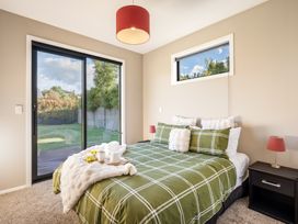 A bedroom with a bed and sliding door at Lake Hawea Holiday Home in Wanaka