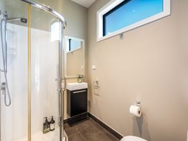 A bathroom with a shower, sink, mirror, and toilet at Lake Hawea Holiday Home in Wanaka