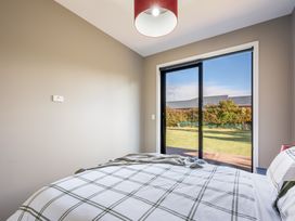A bedroom with a bed and a window leading to outside at Lake Hawea Holiday Home in Wanaka