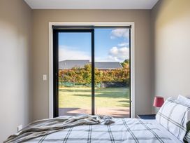 A bedroom with a bed and a sliding door leading to a garden at Lake Hawea Holiday Home in Wanaka