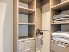 A closet with shelves and drawers containing blankets and hangers at Lake Hawea Holiday Home Wanaka