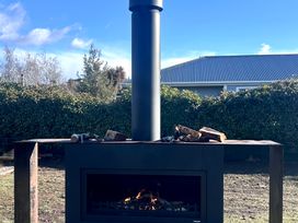 An outdoor fireplace with logs at Hawea Horizon - Lake Hawea Holiday Home in Lake Hawea