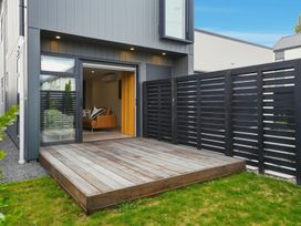 An outdoor area with wooden decking and a fence at Bliss at Madras - Christchurch Holiday Home