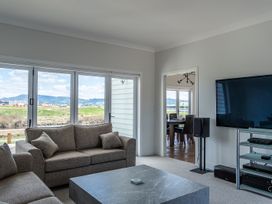 A living room with a sofa and a television at Sunlit Shores - Papamoa Holiday Homes, Papamoa