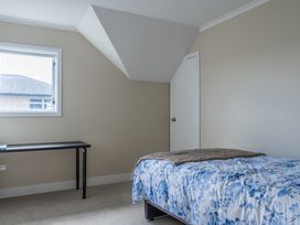A bedroom with a bed and a table at Sunlit Shores - Papamoa Holiday Homes, Papamoa