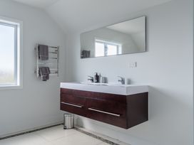 A bathroom with sink and mirror at Sunlit Shores - Papamoa Holiday Homes Papamoa