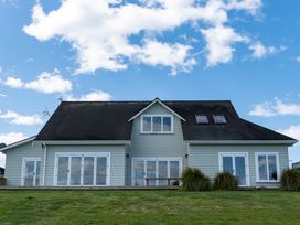 A house with multiple windows and a grassy area at Sunlit Shores - Papamoa Holiday Homes Papamoa