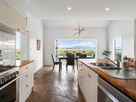 A kitchen with an open view to a dining area at Sunlit Shores - Papamoa Holiday Homes, Papamoa