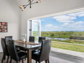 A dining room with a large table and black chairs at Sunlit Shores - Papamoa Holiday Homes, Papamoa