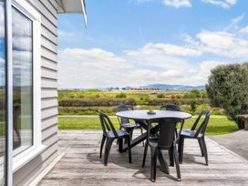 An outdoor seating area with a table and chairs at Sunlit Shores - Papamoa Holiday Homes, Papamoa