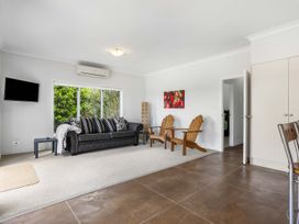 A living room with a sofa and armchairs at Sunlit Shores - Papamoa Holiday Homes Papamoa