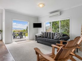A living room with a sofa and armchair at Sunlit Shores - Papamoa Holiday Homes Papamoa
