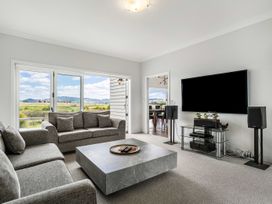 A living room with a sofa, coffee table, and television at Sunlit Shores - Papamoa Holiday Homes, Papamoa