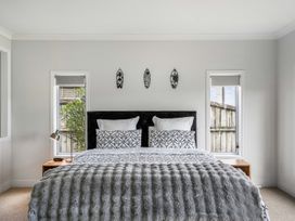 A bedroom with a bed and windows at Sunlit Shores - Papamoa Holiday Homes, Papamoa