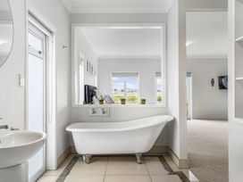 A bathroom with a bathtub and sink at Sunlit Shores - Papamoa Holiday Homes, Papamoa