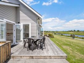 An outdoor deck with a table and chairs at Sunlit Shores - Papamoa Holiday Homes in Papamoa