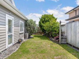 A garden with grass and plants at Sunlit Shores - Papamoa Holiday Homes Papamoa