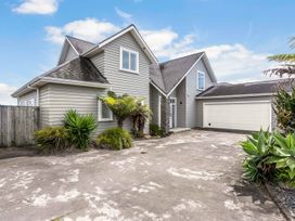 An outdoor view of a house with a garage and plants at Sunlit Shores - Papamoa Holiday Homes, Papamoa