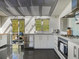 A kitchen with appliances and windows at Lyttelton Holiday Home in Lyttelton