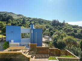 A house with a deck and surrounding trees at Lyttelton Holiday Home in Lyttelton