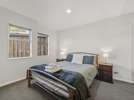A bedroom with a bed and windows at Lyttelton Holiday Home in Lyttelton