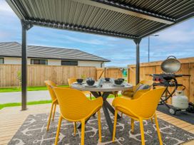 An outdoor patio with a dining table and yellow chairs at Sun and Sea Sanctuary - Whitianga