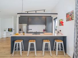 A kitchen with bar stools and appliances at Sun and Sea Sanctuary - Whitianga