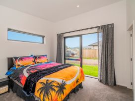 A bedroom with a bed and sliding door at Sun and Sea Sanctuary - Whitianga